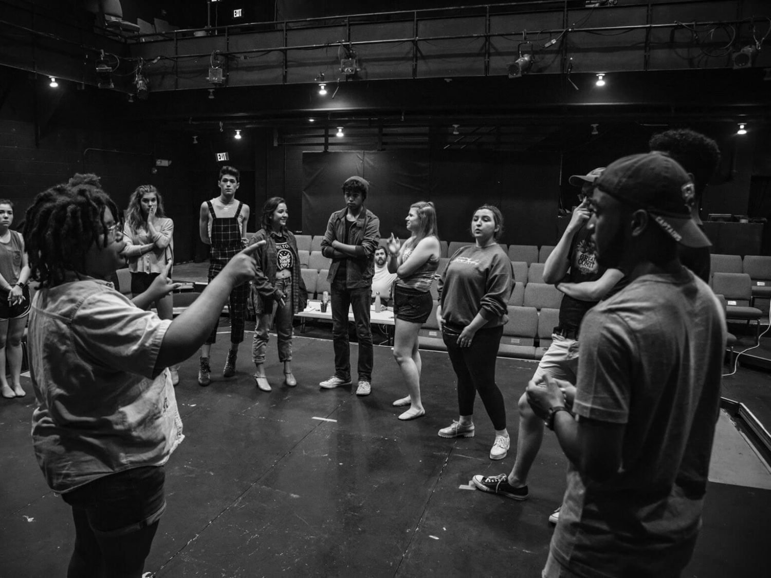 black and white photo of actors on stage standing in a circle
