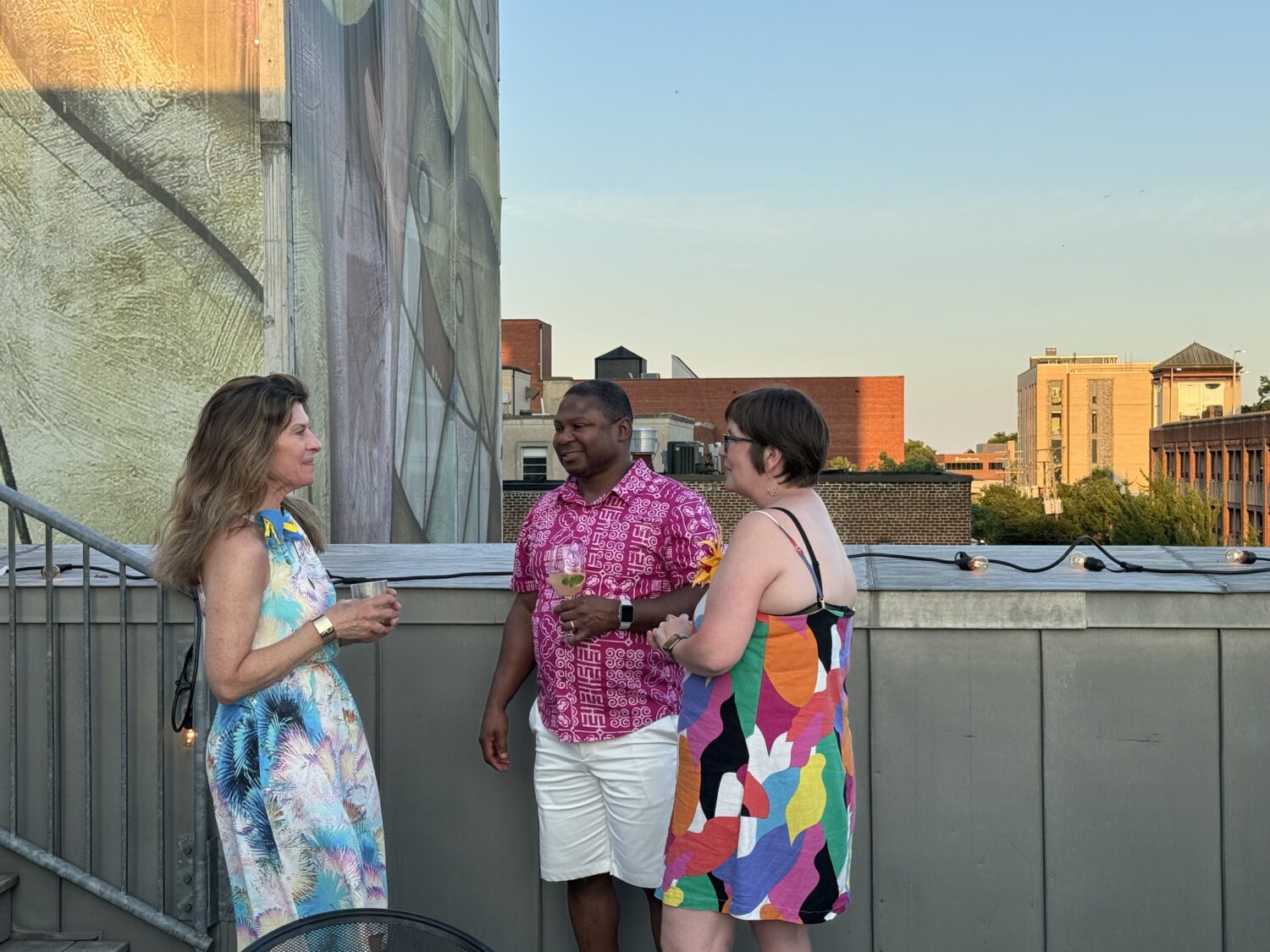 A group of 3 people enjoying drinks on the rooftop terrace at Live Arts Theater.